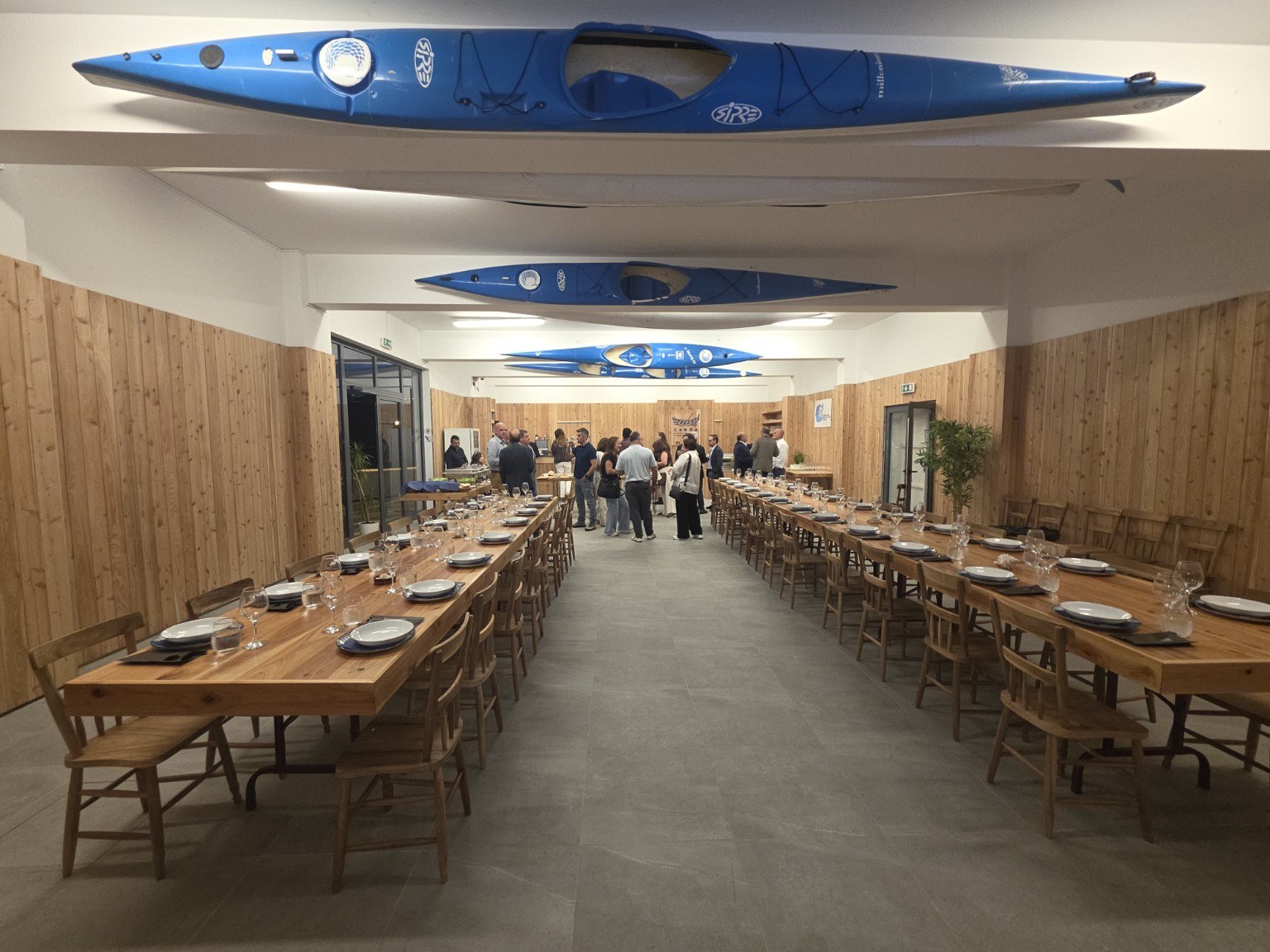 Sala Canôa preparada para um jantar, com mesas corridas e canoas suspensas